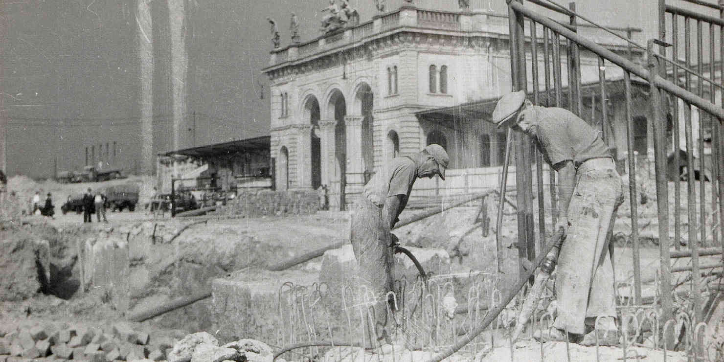 Arbeiter vor einem kriegbeschädigten Bahnhofsgebäude